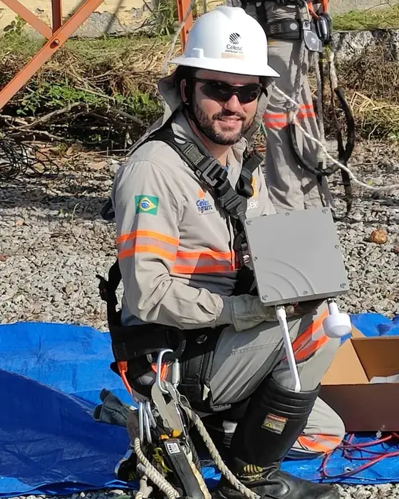 Eletricista com equipamento de segurança segurando um sensor Cigarra antes da instalação
