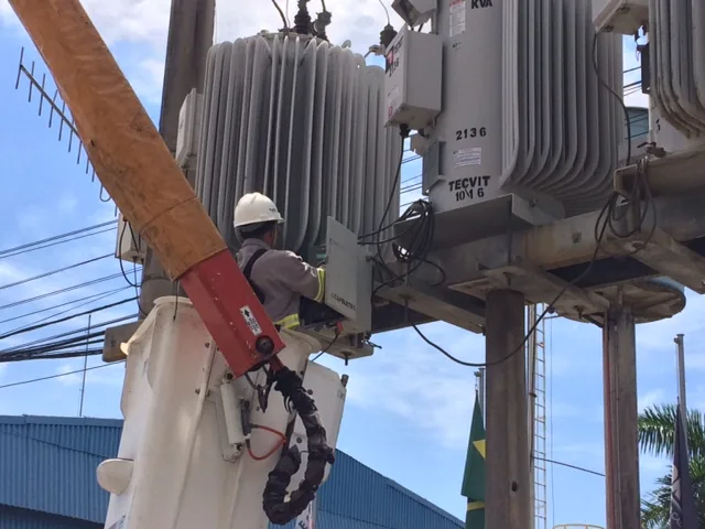 Técnico instalando equipamento de medição em regulador de tensão de média tensão